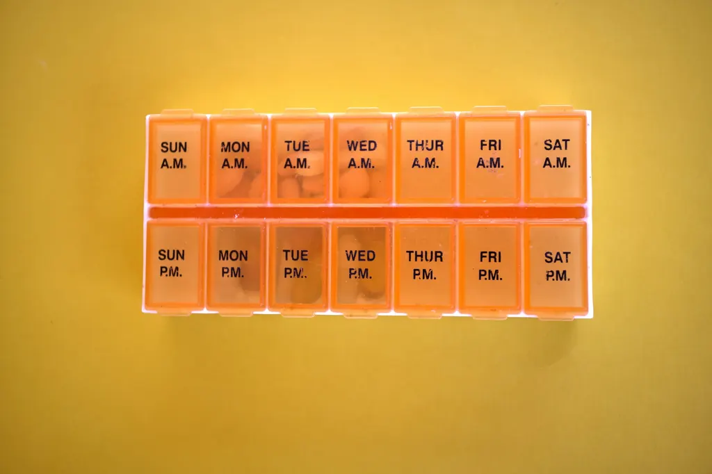 An orange weekly pill organizer with morning and evening compartments
