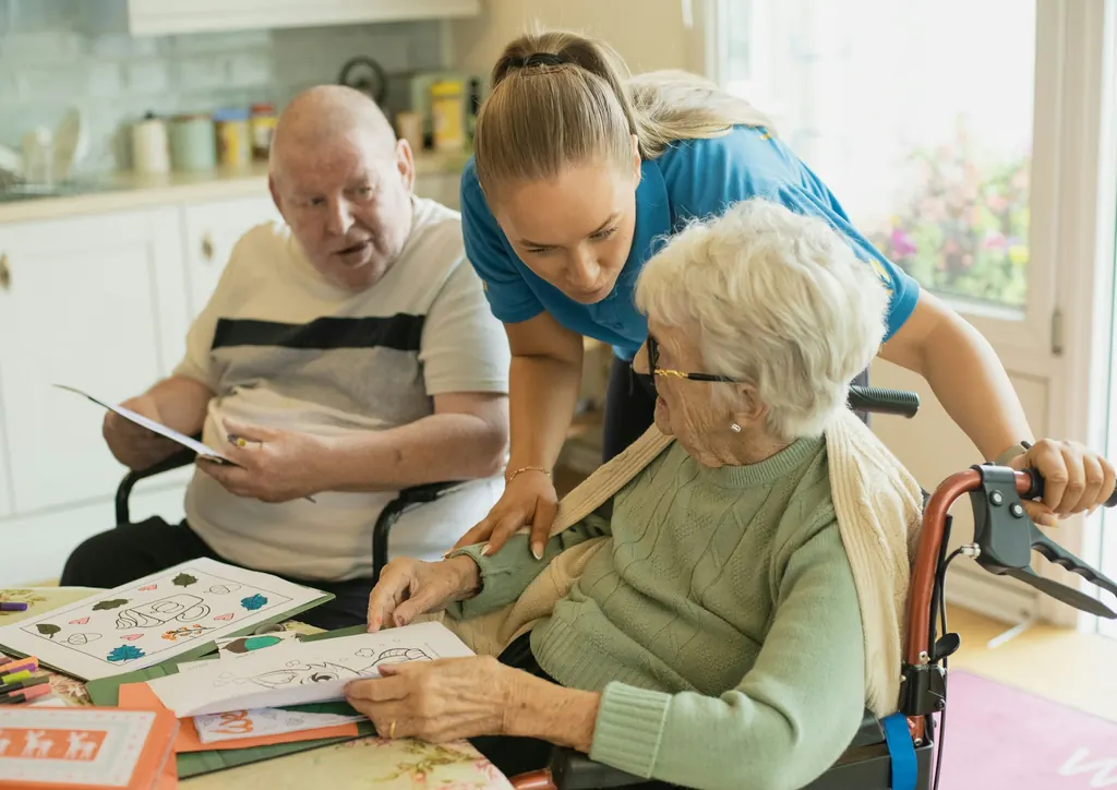 A caregiver guides an older couple through a hands on activity at a table