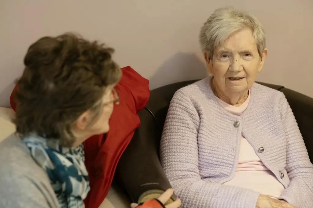 Two women sit together on a sofa in quiet conversation